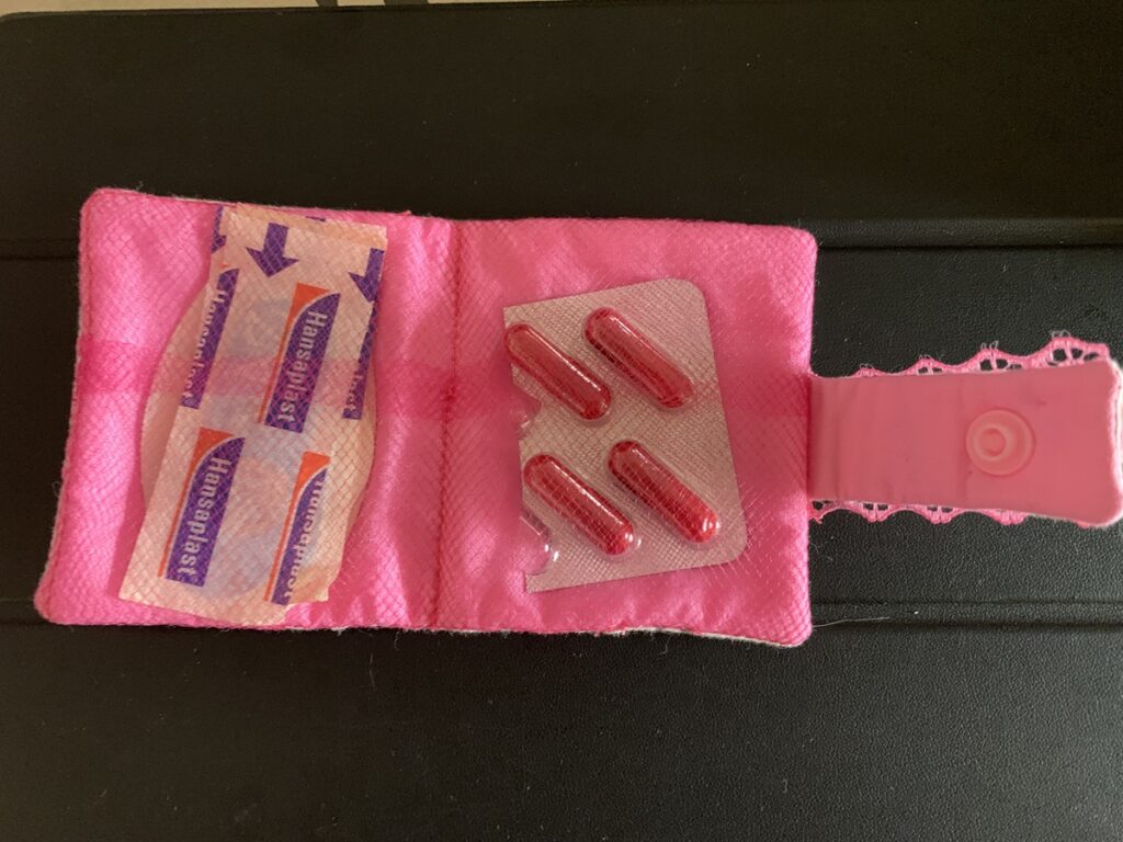 Interior del botiquín para el bolso con forro rosa y compartimentos de tul para guardar medicación y tiritas.