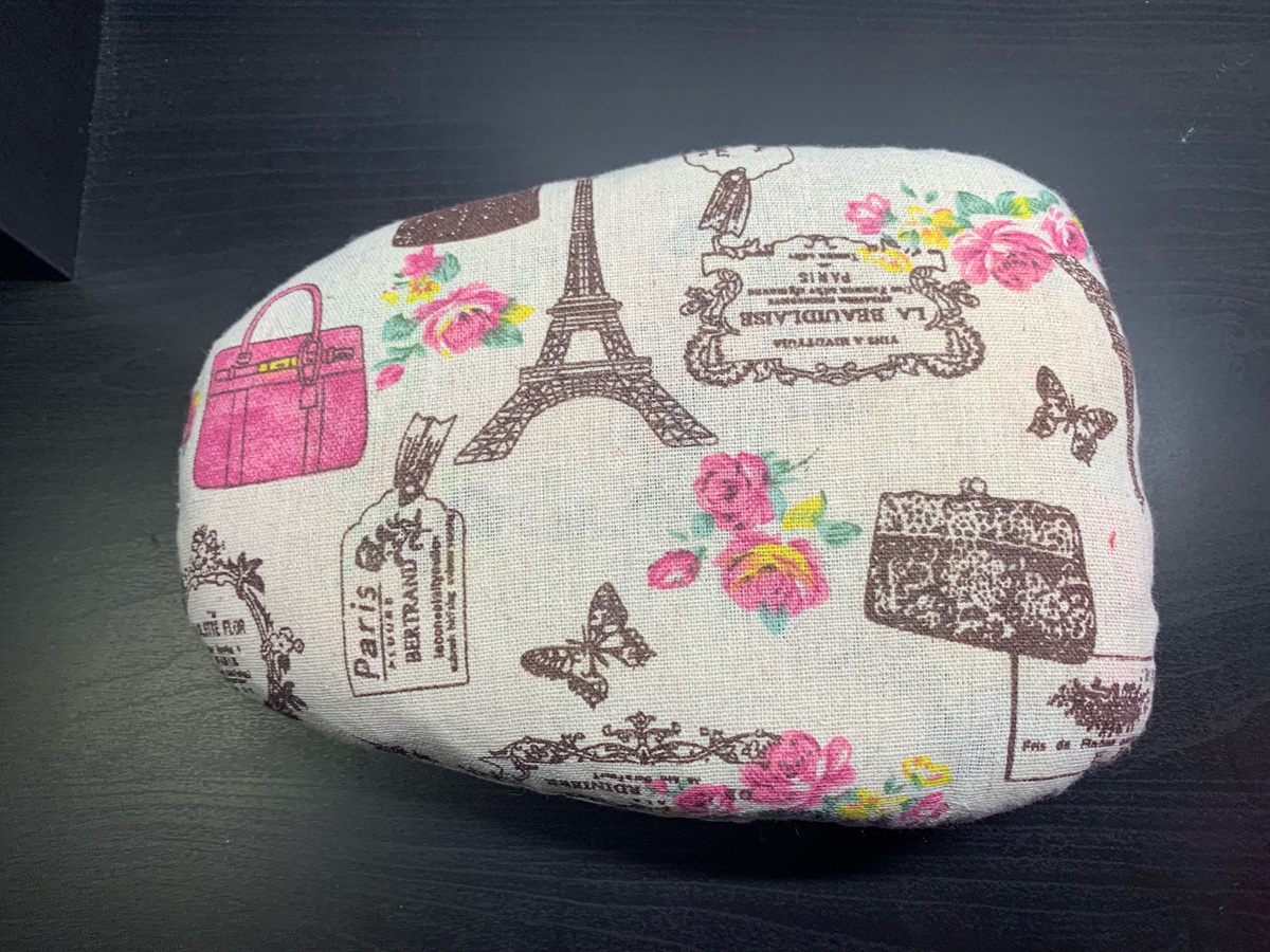 Cojín de sastre de forma ovalada confeccionado con tela de lino estampada con motivos de París.