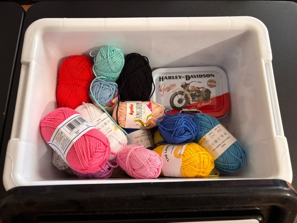 Caja con ovillos de lana de distintos colores para proyectos de crochet.
